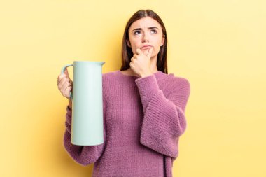 Genç İspanyol kadın düşünüyor, kuşkulu ve şaşkın hissediyor. Kahve termosu kavramı