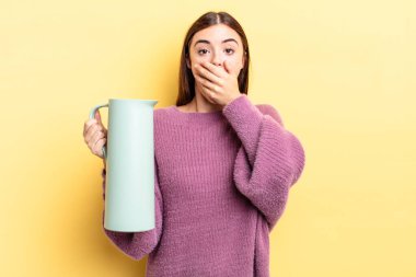 Genç İspanyol kadın şok olmuş ellerle ağzını kapatıyor. Kahve termosu kavramı