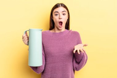 Genç İspanyol kadın şok olmuş ve şaşırmış hissediyor. Kahve termosu kavramı