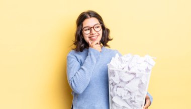 Genç İspanyol kadın mutlu ve kendinden emin bir ifadeyle gülümsüyor, elleri çenesinde başarısız çöp konsepti.