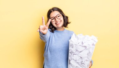 Genç İspanyol kadın gülümseyen ve mutlu görünen, işaret eden zafer veya barış başarısız çöp konsepti