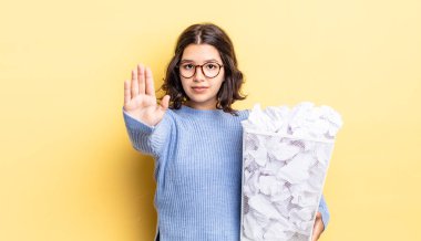 Genç İspanyol kadın ciddi görünüyor. Avuç içini gösteriyor. Durdurma hareketi, başarısız çöp kavramı.