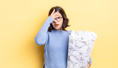 Genç İspanyol kadın şok olmuş, korkmuş ya da korkmuş görünüyor. Yüzü el kaplaması çöp konseptiyle kaplanmış.