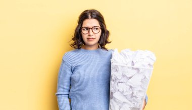 Genç İspanyol kadın üzgün, üzgün ya da kızgın hissediyor ve başarısız çöp konseptine bakıyor.