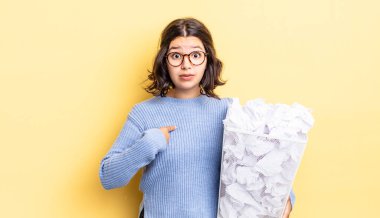 Şok olmuş ve ağzı açık bir şekilde şaşırmış genç İspanyol kadın kendini başarısız çöp konseptine işaret ediyor.