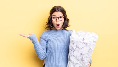 Genç İspanyol kadın şaşırmış ve şok olmuş görünüyor, çenesi düşmüş, elinde bir nesne başarısız çöp kavramı tutuyordu.