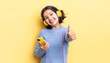 Genç İspanyol kadın gururlu, olumlu bir şekilde gülümsüyor. kulaklıklar ve akıllı telefon konsepti