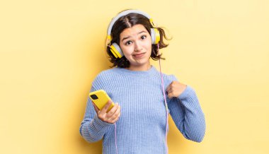 Genç İspanyol kadın kibirli, başarılı, pozitif ve gururlu görünüyor. kulaklıklar ve akıllı telefon konsepti