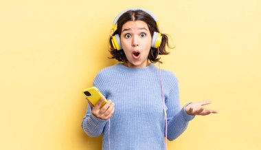 Genç İspanyol kadın inanılmaz bir sürprizle şaşkına dönmüş ve hayrete düşmüştü. kulaklıklar ve akıllı telefon konsepti