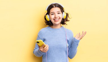 Genç İspanyol kadın kendini mutlu hissediyor, bir çözüm ya da fikir bulduğuna şaşırıyor. kulaklıklar ve akıllı telefon konsepti