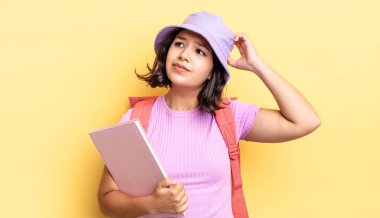 Genç İspanyol kadın mutlu bir şekilde gülümsüyor ve hayal kuruyor ya da şüphe ediyor. okul konseptine geri dön