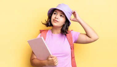 Genç İspanyol kadın şaşkın ve kafası karışık, kaşınan bir kafa hissediyor. okul konseptine geri dön