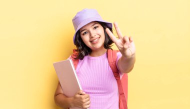 Genç İspanyol kadın gülümsüyor ve mutlu görünüyor, zafer ya da barış işareti yapıyor. okul konseptine geri dön