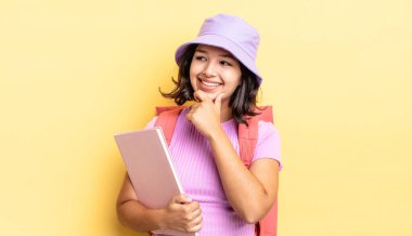 Genç İspanyol kadın mutlu ve kendinden emin bir ifadeyle gülümsüyor. Elleri çenesinde. okul konseptine geri dön