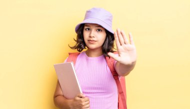 Genç İspanyol kadın ciddi görünüyor. Avuç içini gösteriyor. Durdurma hareketi yapıyor. okul konseptine geri dön