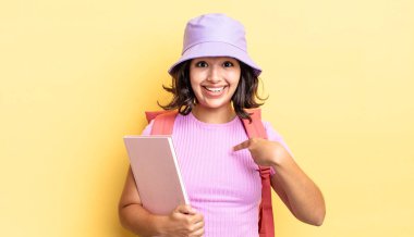 Genç İspanyol kadın kendini mutlu hissediyor ve heyecanla kendini işaret ediyor. okul konseptine geri dön