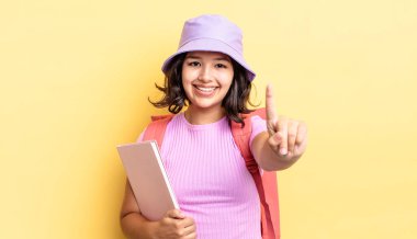 Genç İspanyol kadın gülümsüyor ve arkadaş canlısı görünüyor, bir numarayı gösteriyor. okul konseptine geri dön