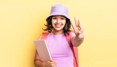 Genç İspanyol kadın gülümsüyor ve arkadaş canlısı görünüyor, üç numarayı gösteriyor. okul konseptine geri dön