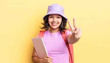 Genç İspanyol kadın gülümsüyor ve arkadaş canlısı görünüyor, iki numarayı gösteriyor. okul konseptine geri dön