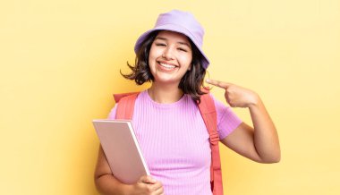 Genç İspanyol kadın kendine güvenerek gülümsüyor ve kendi gülüşünü gösteriyor. okul konseptine geri dön