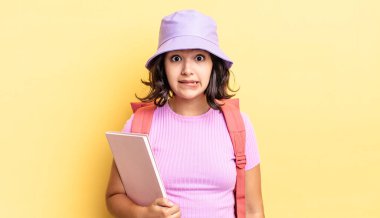 Genç İspanyol kadın şaşkın ve şaşkın görünüyor. okul konseptine geri dön