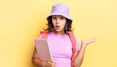 Genç İspanyol kadın şaşırmış ve şok olmuş görünüyor. Çenesi düşmüş ve elinde bir nesne tutuyor. okul konseptine geri dön