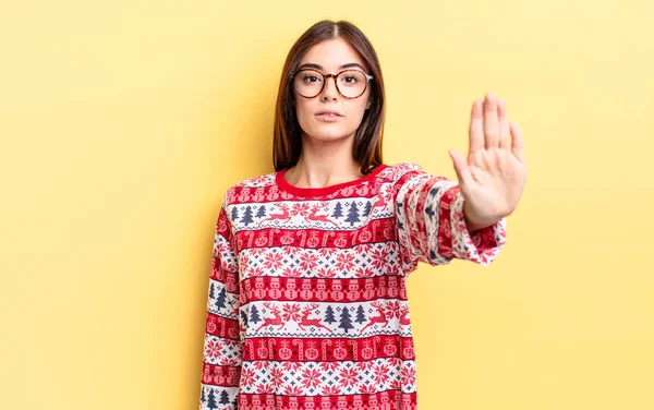 Genç İspanyol kadın ciddi görünüyor. Avuç içini gösteriyor. Durdurma hareketi yapıyor. Chistmas ve yeni yıl konsepti