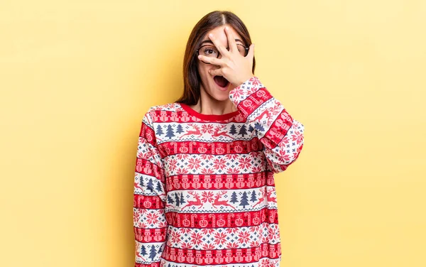 Genç İspanyol bir kadın şok olmuş, korkmuş ya da korkmuş görünüyor. Yüzü elle kapatılmış. Chistmas ve yeni yıl konsepti
