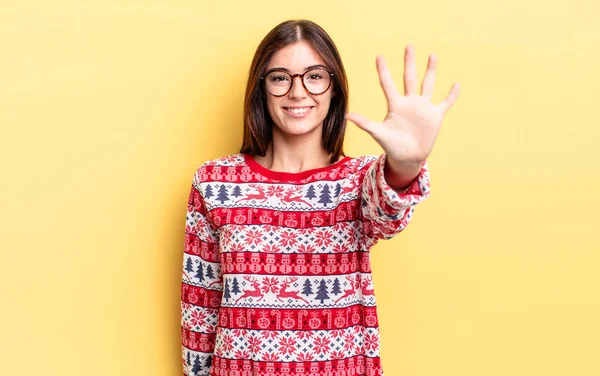 Genç İspanyol kadın gülümsüyor ve arkadaş canlısı görünüyor, beş numarayı gösteriyor. Chistmas ve yeni yıl konsepti