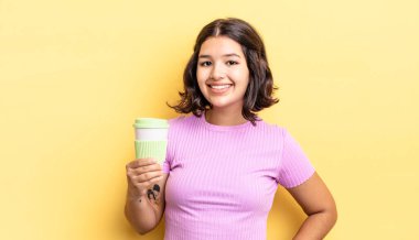 Genç İspanyol kadın mutlu bir şekilde gülümsüyor, eli kalçasında ve kendinden emin. kahve konseptini kaldır.