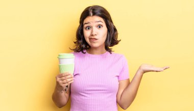 Genç İspanyol kadın şaşkın, şaşkın ve şüpheci hissediyor. kahve konseptini kaldır.