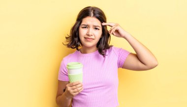 Genç İspanyol kadın şaşkın ve şaşkın hissediyor, senin deli olduğunu gösteriyor. kahve konseptini kaldır.