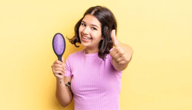 Genç İspanyol kadın gururlu, olumlu bir şekilde gülümsüyor. saç fırçası konsepti