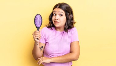 Genç İspanyol kadın omuz silkiyor, kafası karışık ve kararsız. saç fırçası konsepti