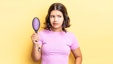 Genç İspanyol kadın üzgün, üzgün ya da kızgın hissediyor ve yana bakıyor. saç fırçası konsepti