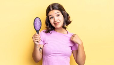 Genç İspanyol kadın kibirli, başarılı, pozitif ve gururlu görünüyor. saç fırçası konsepti