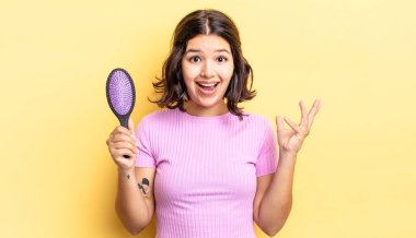 Genç İspanyol kadın kendini mutlu hissediyor, bir çözüm ya da fikir bulduğuna şaşırıyor. saç fırçası konsepti