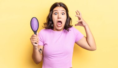 Genç İspanyol kadın ellerini havaya kaldırarak çığlık atıyor. saç fırçası konsepti