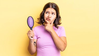 Genç İspanyol kadın düşünüyor, kuşkulu ve şaşkın hissediyor. saç fırçası konsepti