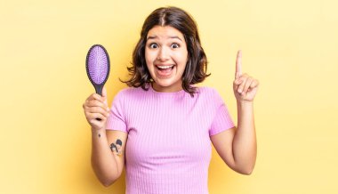 Genç İspanyol kadın bir fikri fark ettikten sonra mutlu ve heyecanlı bir dahi gibi hissediyor. saç fırçası konsepti