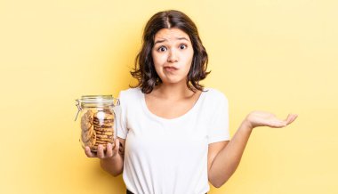 Genç İspanyol kadın şaşkın, şaşkın ve şüpheci hissediyor. kurabiye şişesi konsepti