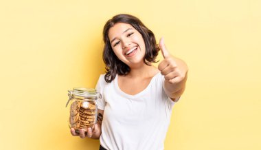 Genç İspanyol kadın gururlu, olumlu bir şekilde gülümsüyor. kurabiye şişesi konsepti