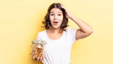 Genç İspanyol kadın mutlu, şaşkın ve şaşırmış görünüyor. kurabiye şişesi konsepti