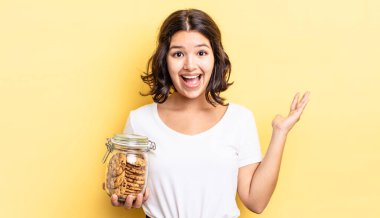 Genç İspanyol kadın kendini mutlu hissediyor ve inanılmaz bir şeye hayret ediyor. kurabiye şişesi konsepti