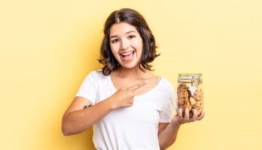 Genç İspanyol kadın heyecanlı ve şaşırmış görünüyor. kurabiye şişesi konsepti