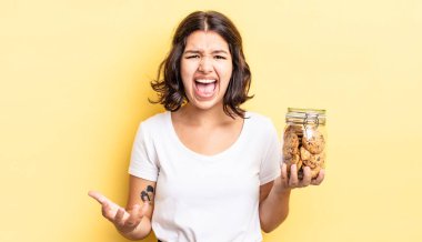 Genç İspanyol kadın kızgın, sinirli ve hayal kırıklığına uğramış görünüyor. kurabiye şişesi konsepti