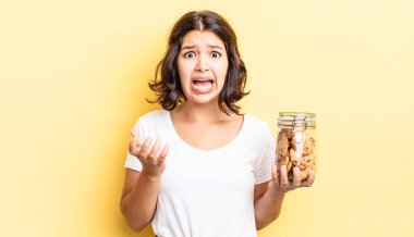 Genç İspanyol kadın umutsuz, hayal kırıklığına uğramış ve stresli görünüyor. kurabiye şişesi konsepti