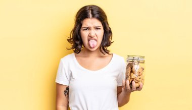 Genç İspanyol kadın iğreniyor, sinirleniyor ve dili dışarı çıkıyor. kurabiye şişesi konsepti