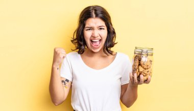 Genç İspanyol kadın öfkeli bir ifadeyle agresif bir şekilde bağırıyor. kurabiye şişesi konsepti