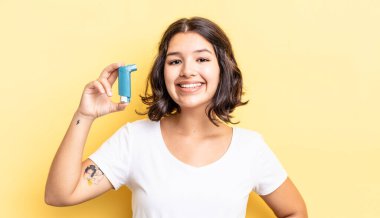 Genç İspanyol kadın mutlu bir şekilde gülümsüyor, eli kalçasında ve kendinden emin. astım konsepti